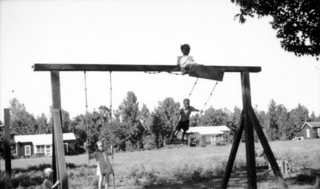 Children playing on a swings at Delta Cooperative with houses in the background, photo d’illustration